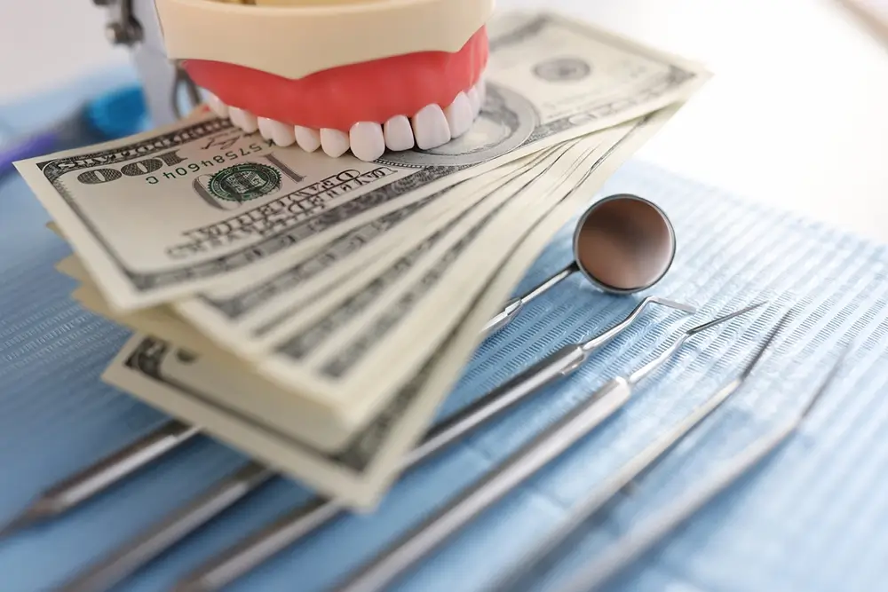 Dental artificial jaw with instruments and one hundred dollar bills on dentist tray